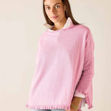 Woman wearing a pink sweater with a white collar against a plain background