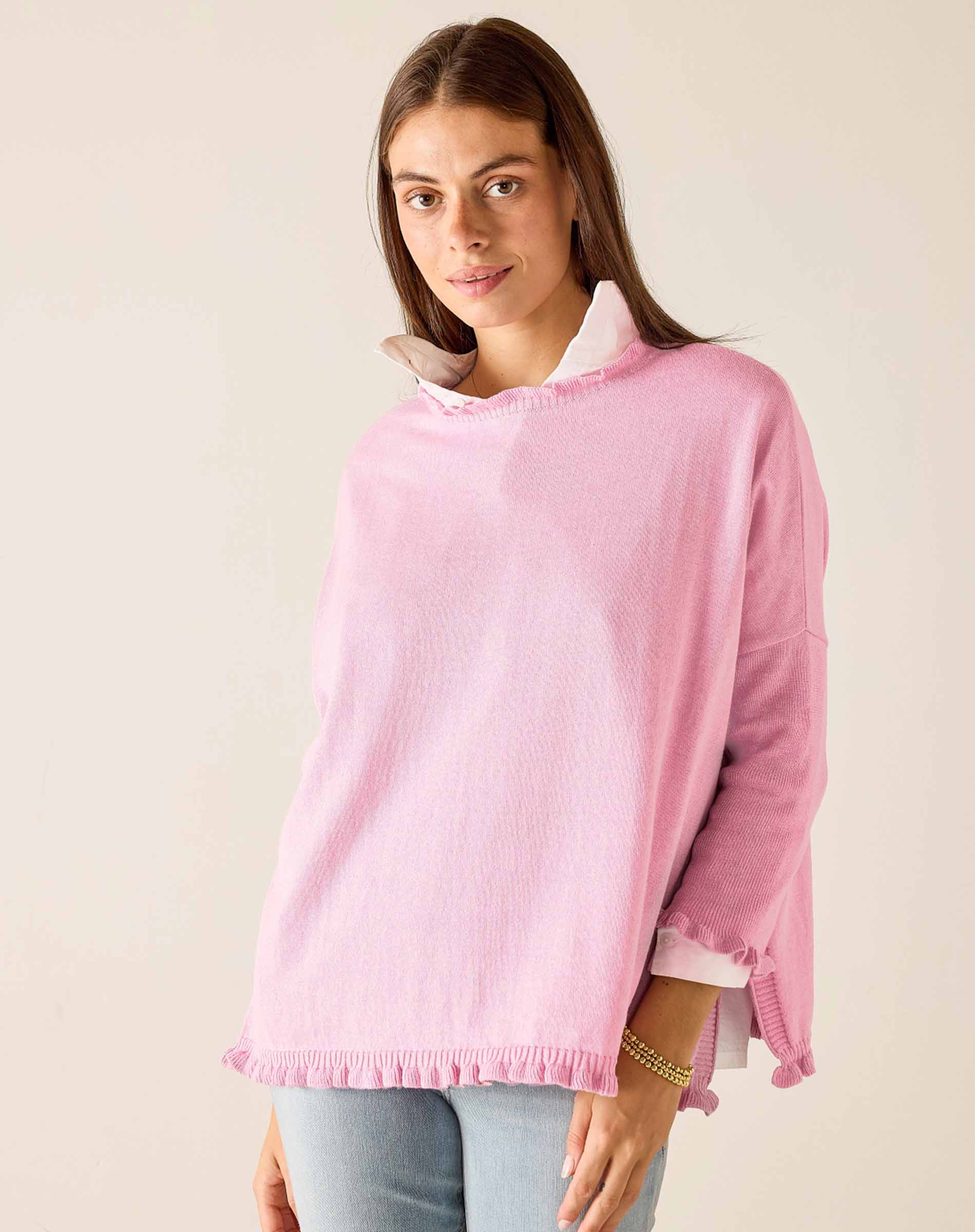 Woman wearing a pink sweater with a white collar against a plain background
