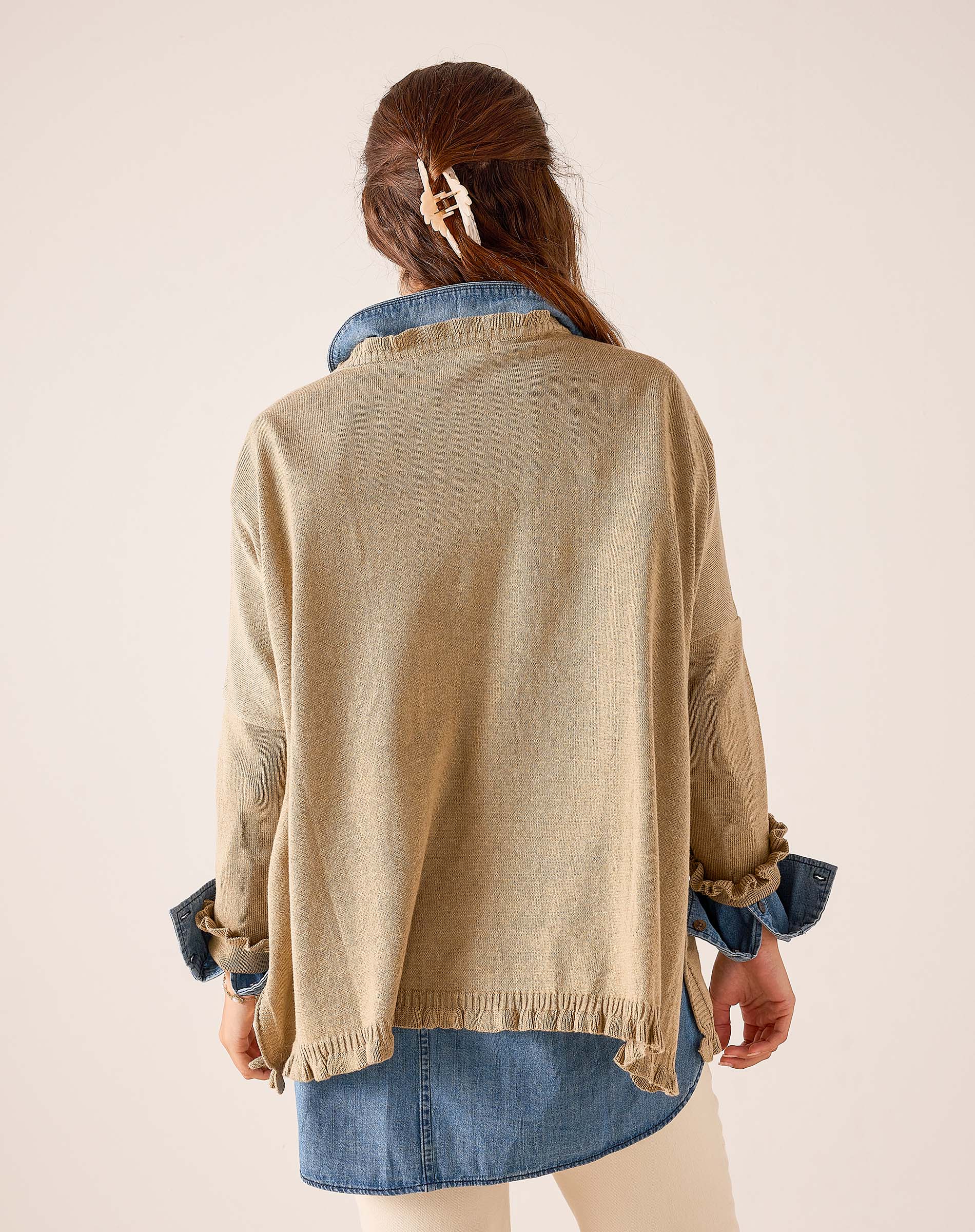 Back view of women's travel-friendly saddle-colored knit Catalina ruffle sweater with ruffled hem and cuffs over a denim shirt.