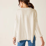Back view of the warm white ruffle knit sweater with a ruffled hem and long sleeves.