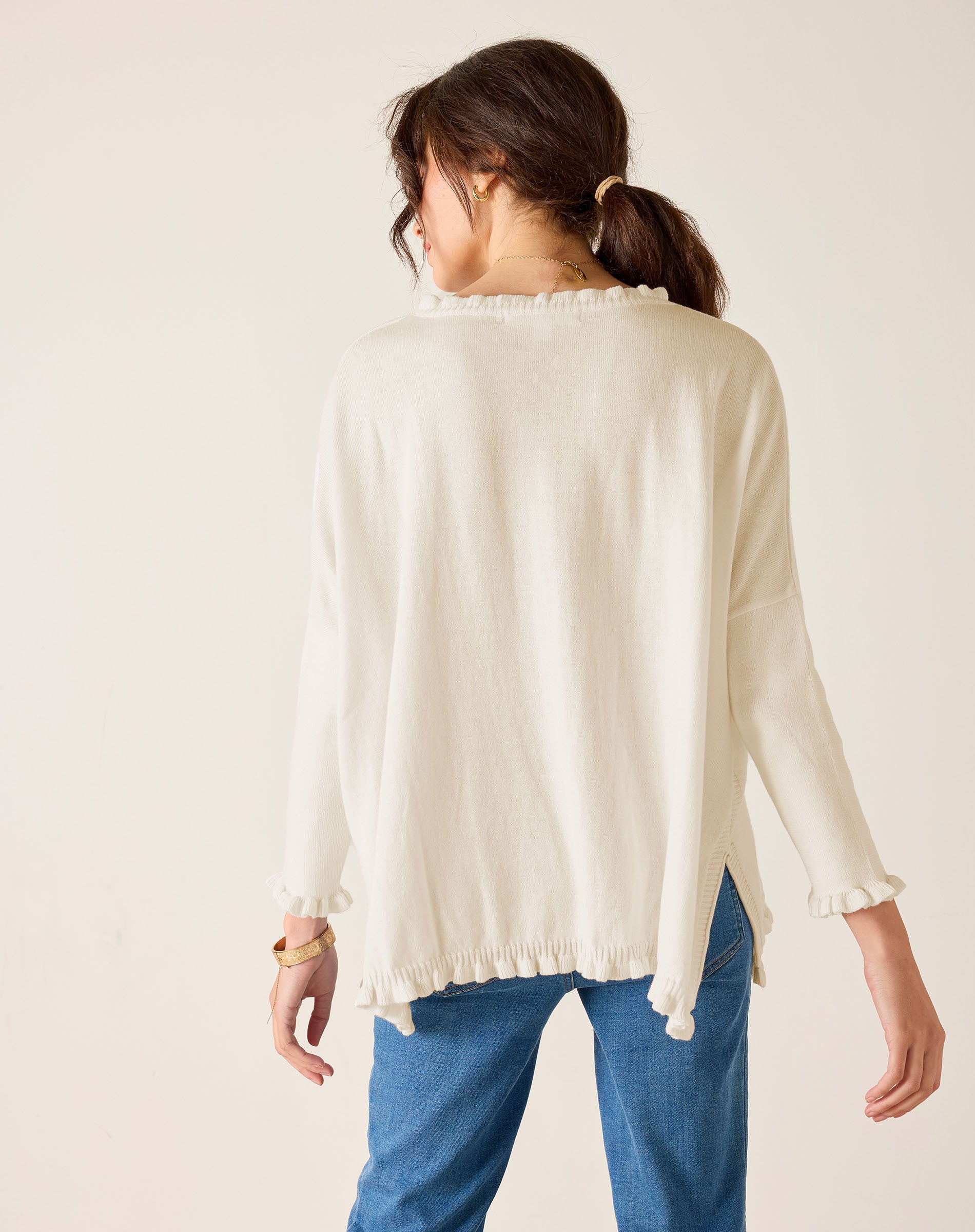 Back view of the warm white ruffle knit sweater with a ruffled hem and long sleeves.