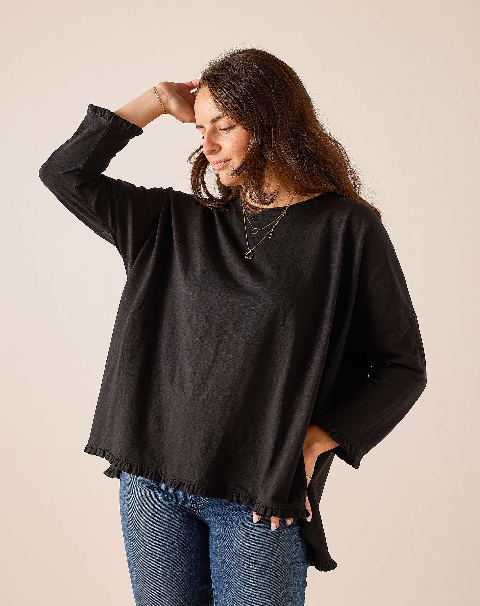 Black relaxed-fit cotton tee with ruffle detailing at the hem and cuffs.