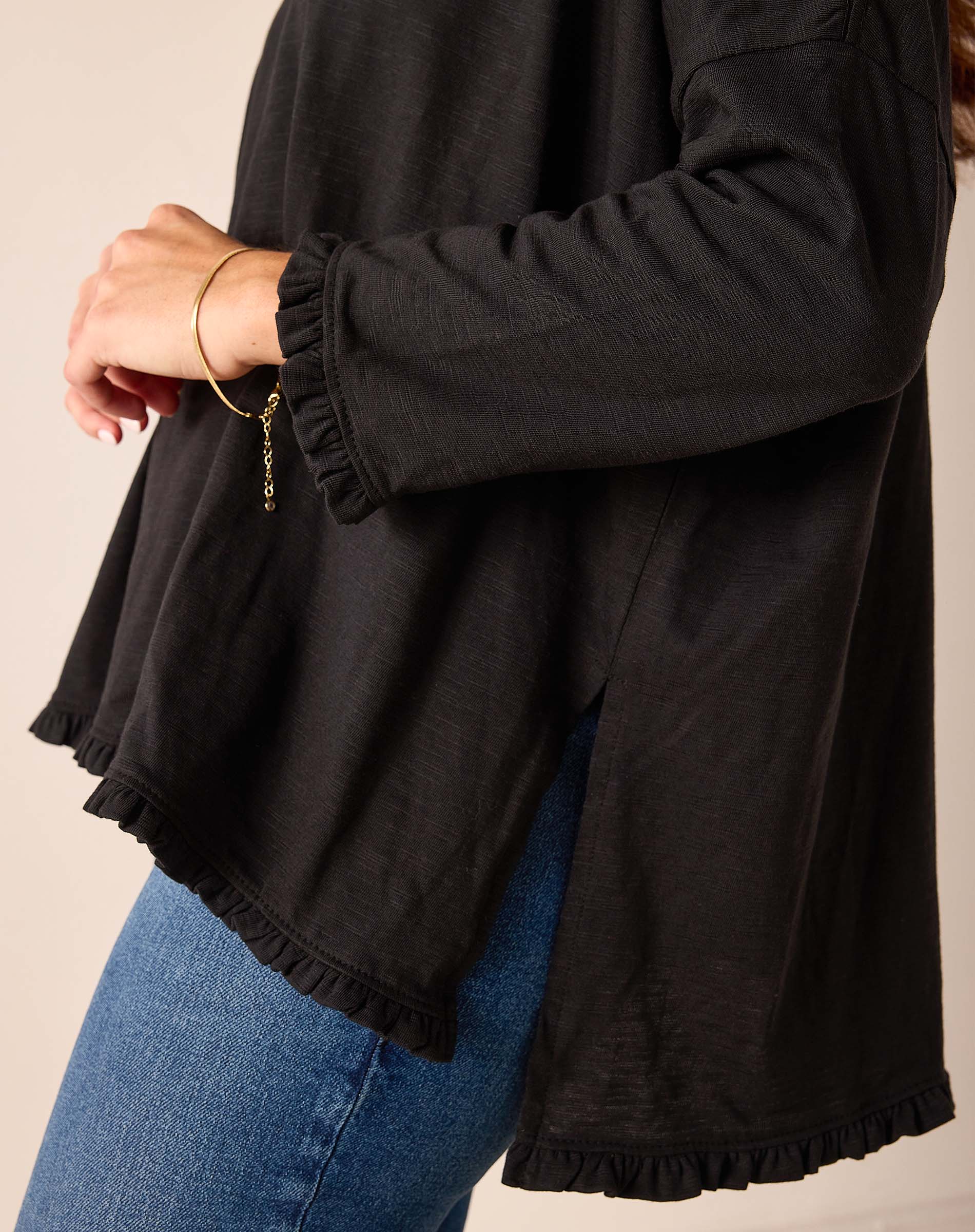 Black ruffled hem tee featuring a relaxed fit and soft cotton texture.