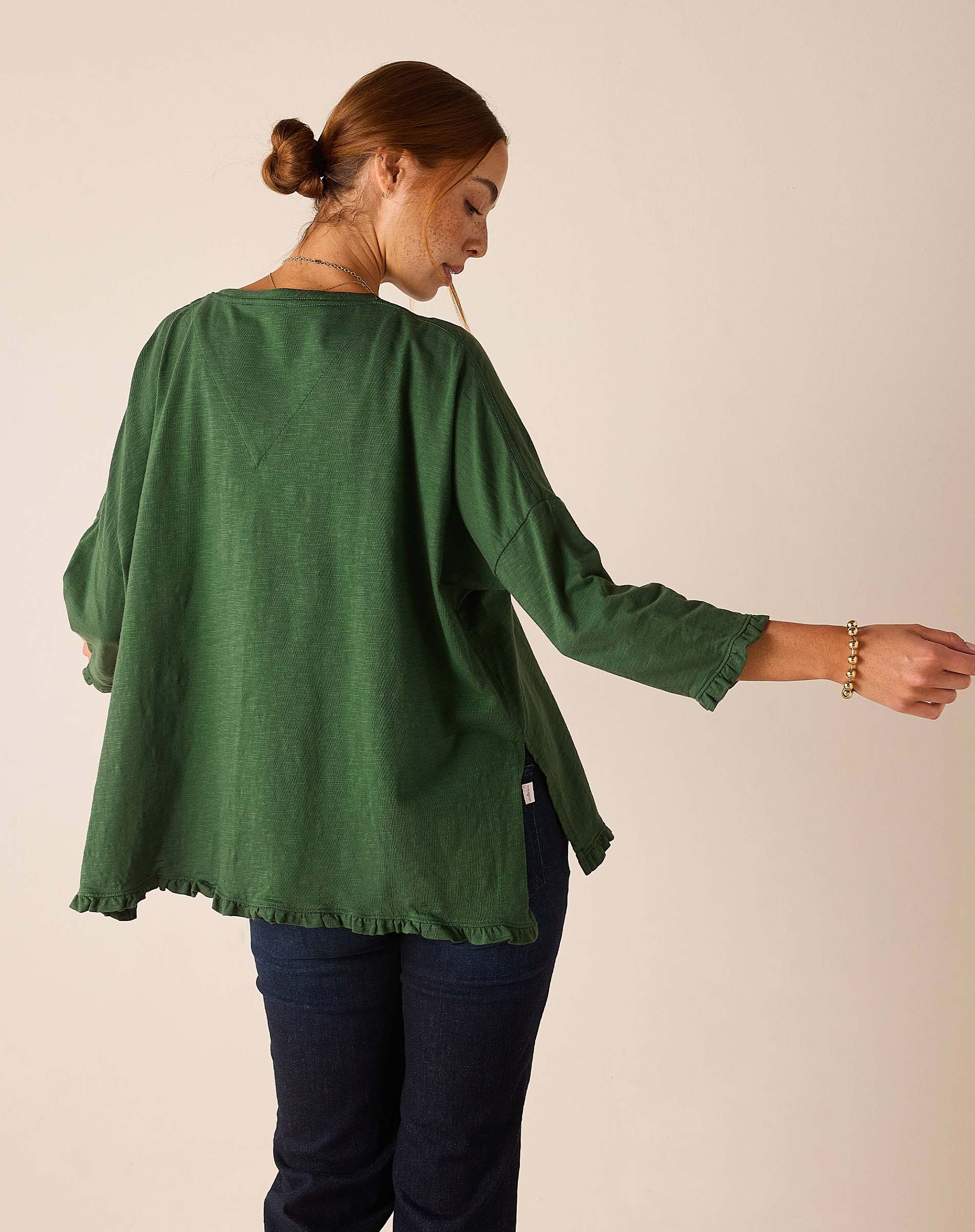 Back view of the fairway green ruffled tee with relaxed fit and loose sleeves.