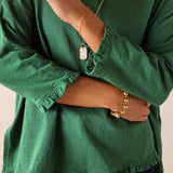 Fairway green ruffled tee with three-quarter sleeves and a ruffled hem.