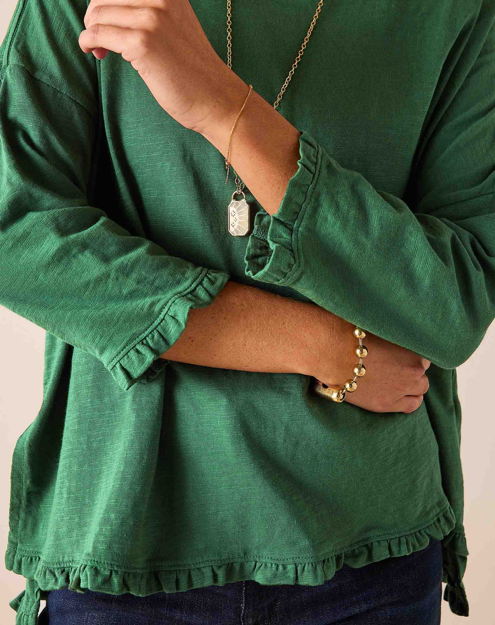 Fairway green ruffled tee with three-quarter sleeves and a ruffled hem.