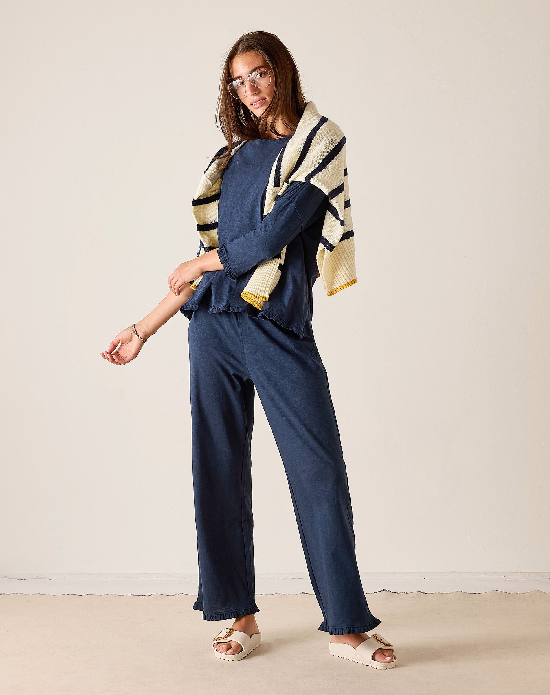 Woman wearing a navy outfit with a patterned cardigan against a plain background