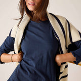 Woman wearing a navy dress with a beige and black striped cardigan against a plain background