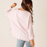 Woman wearing a light pink blouse with a plain background