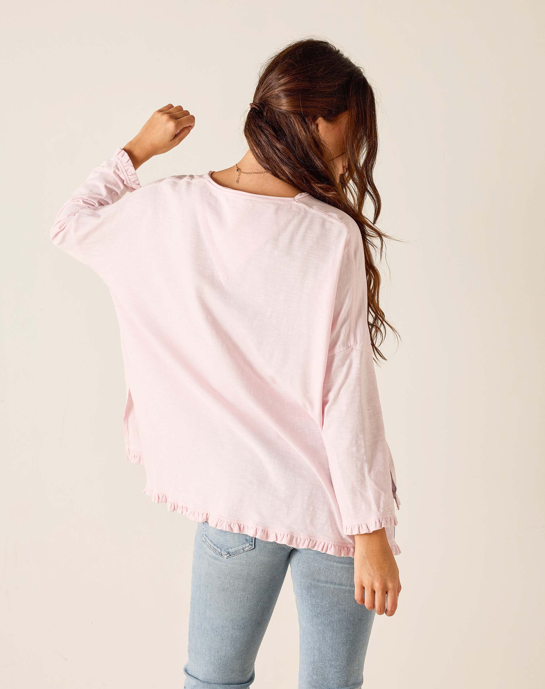 Woman wearing a light pink blouse with a plain background