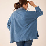 Back view of women's travel-friendly slate blue top with a ruffled hem and striped trim.