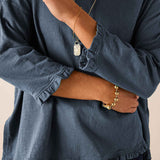 Slate blue ruffled tee with gathered cuffs and a ruffled hemline.