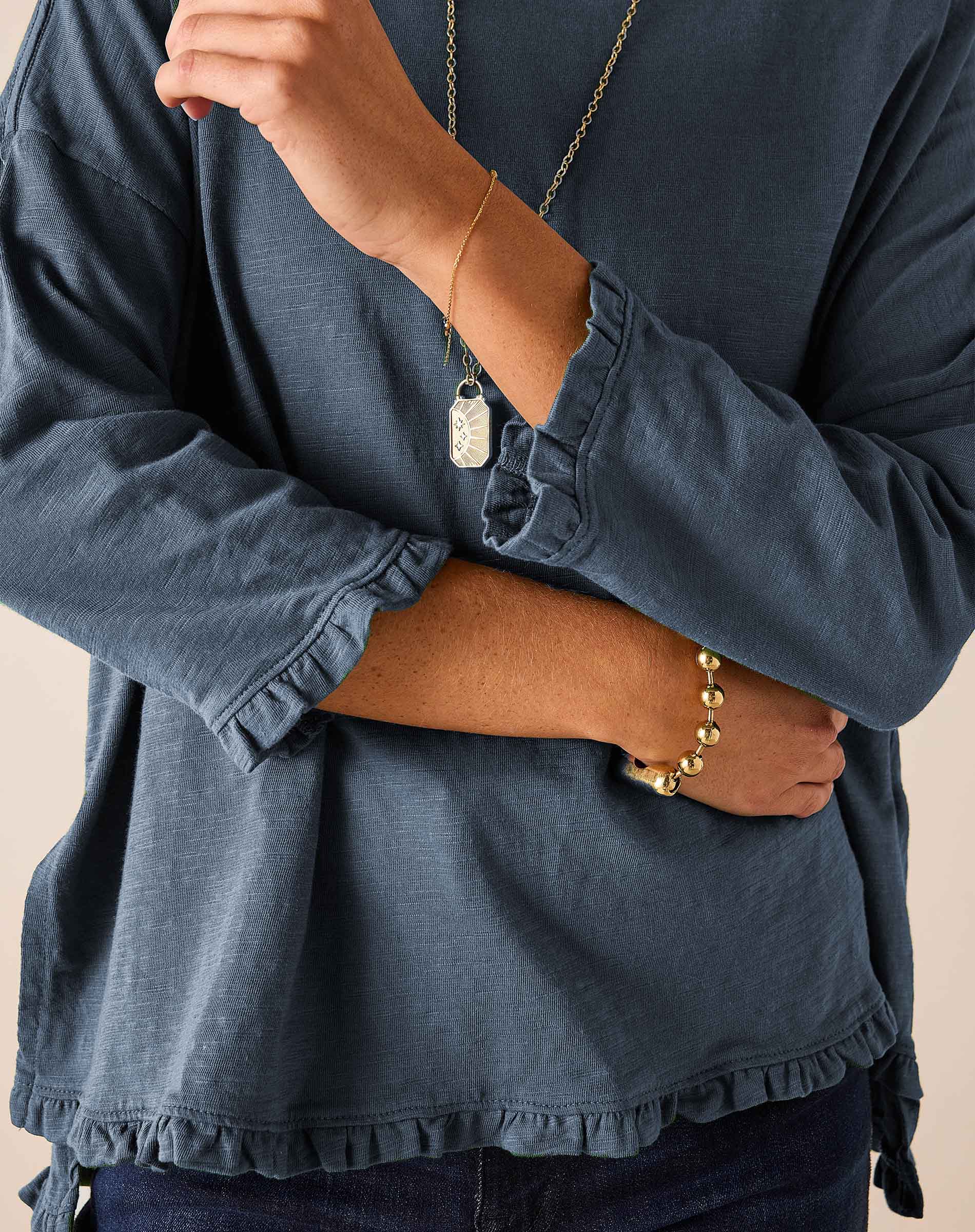 Slate blue ruffled tee with gathered cuffs and a ruffled hemline.