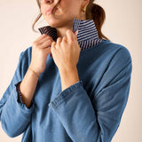 Slate blue ruffled tee with striped neckline and sleeve details.