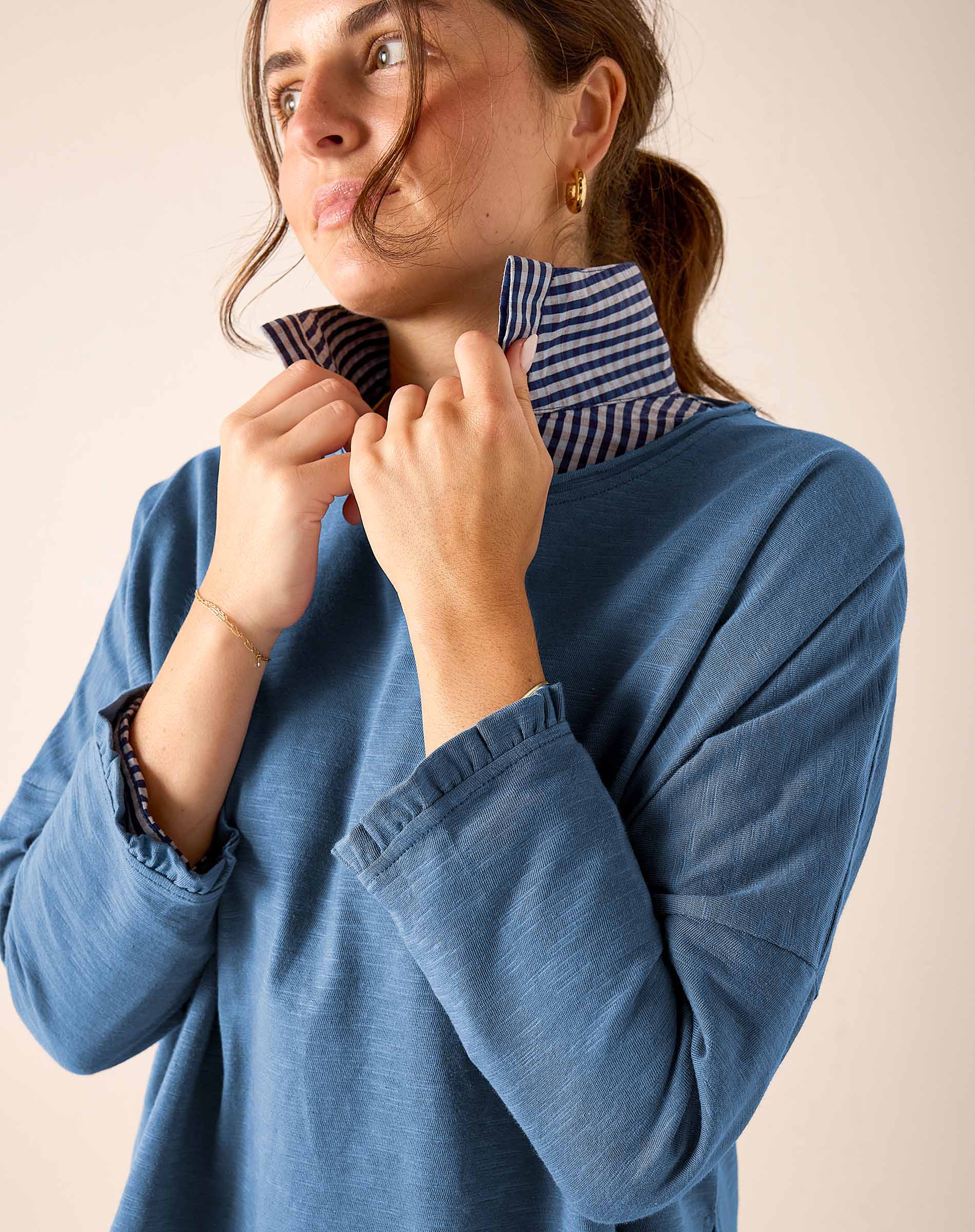 Slate blue ruffled tee with striped trim and gathered cuffs.