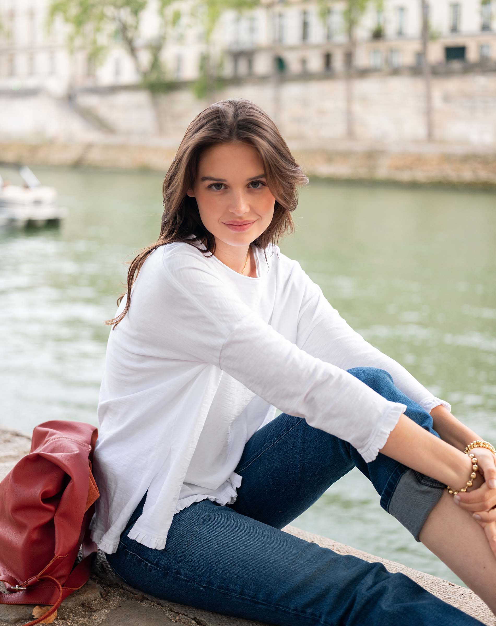 Woman sitting by a river with a blurred background