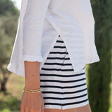 Person wearing a white shirt and black and white striped shorts with a blurred natural background