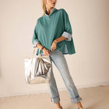 Aqua blue relaxed-fit knit top with half-zip and folded cuffs.