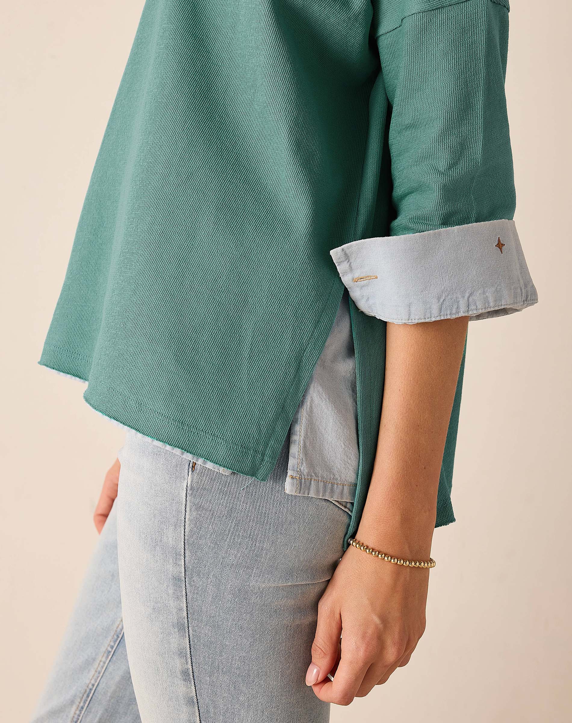 Aqua blue t-shirt featuring a buttoned cuff detail and subtle texture.