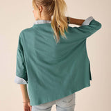 Back view of a woman wearing a women's travel-friendly aqua blue t-shirt with white contrast trim on the sleeves and hem.
