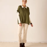 MERSEA women's travel-friendly moss green short-sleeve ruffle sweater layered over a white collared shirt and beige trousers.