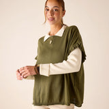 Moss green ruffled sweater worn over a cream-colored long-sleeved top.
