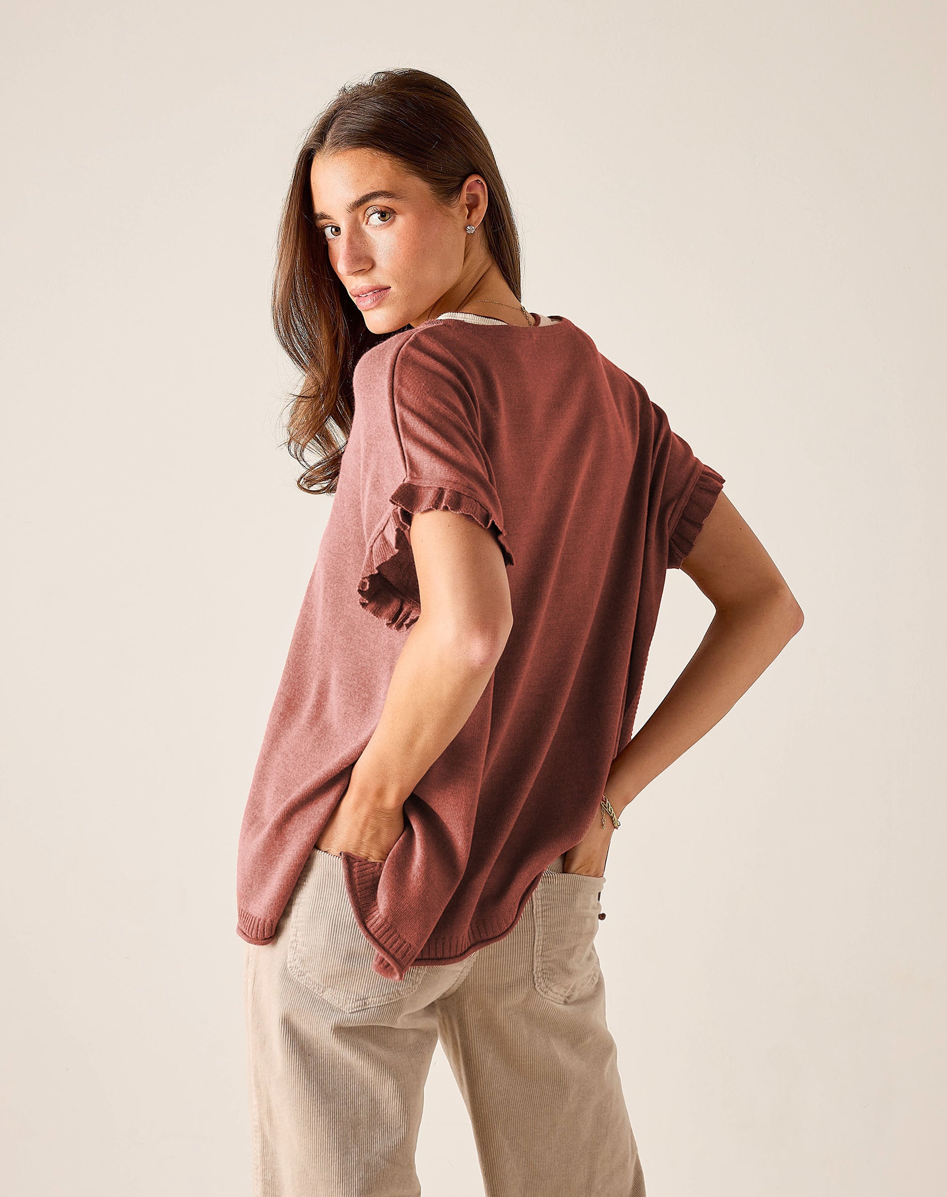 Burnt brick short-sleeve knit top with ruffled edges and a relaxed fit.