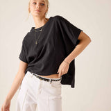 Woman wearing a black oversized t-shirt and white pants on a plain background
