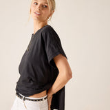 Woman wearing a black t-shirt and white pants against a plain background