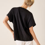 Person wearing a black t-shirt and white pants on a beige background