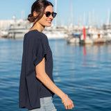 MERSEA women's travel-friendly navy short-sleeve tee worn by a smiling model in a harbor setting.
