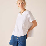 Woman wearing a white t-shirt and blue denim shorts on a beige background