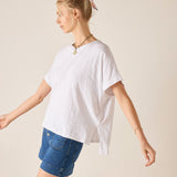 Woman wearing a white oversized t-shirt and denim shorts on a beige background