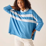 Woman wearing a blue long-sleeve shirt with white stripes on a plain background