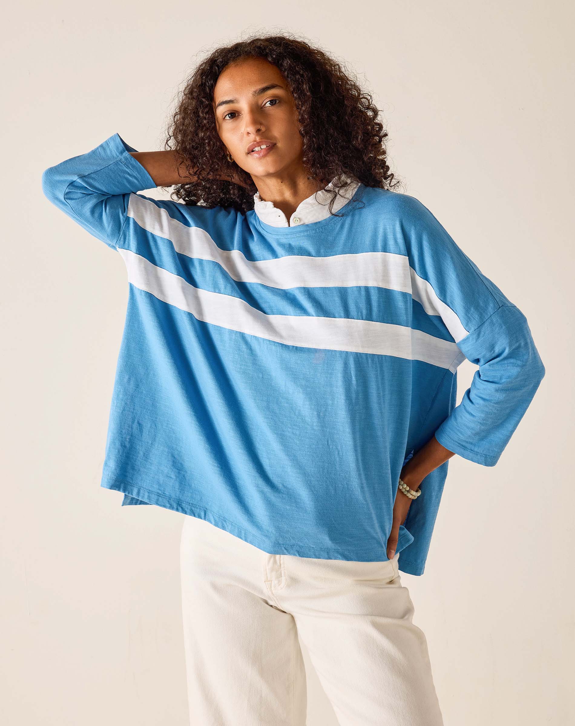 Woman wearing a blue long-sleeve shirt with white stripes on a plain background