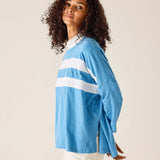 Woman wearing a light blue long-sleeve shirt with white stripes on a plain background