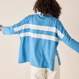 Person wearing a blue cardigan with white stripes from behind on a beige background
