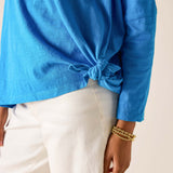 Blue long-sleeve top with a knot detail worn by a person on a neutral background