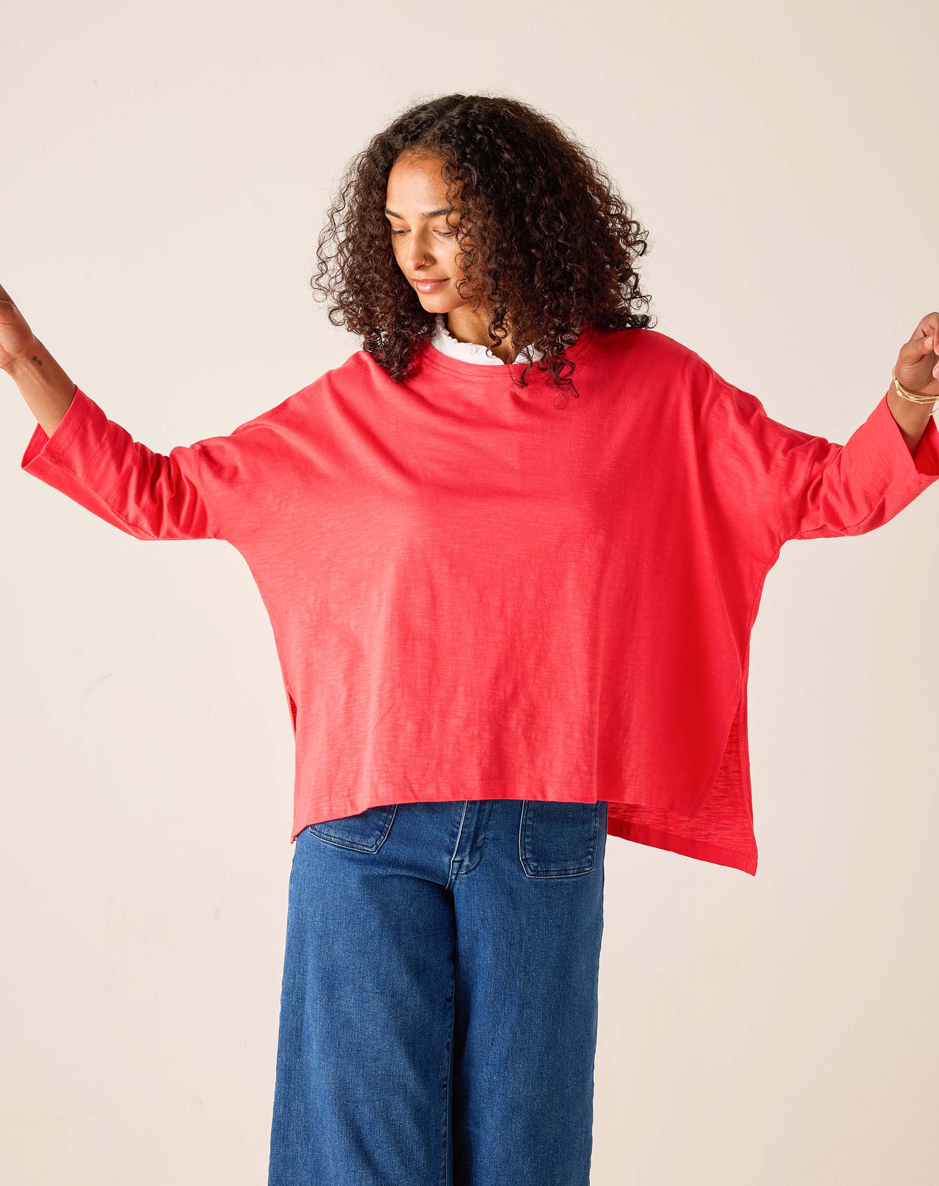Person wearing a red oversized sweater and blue jeans against a plain background