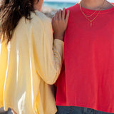 Two people standing close together, one in a yellow shirt and the other in a red shirt, with a blurred background.