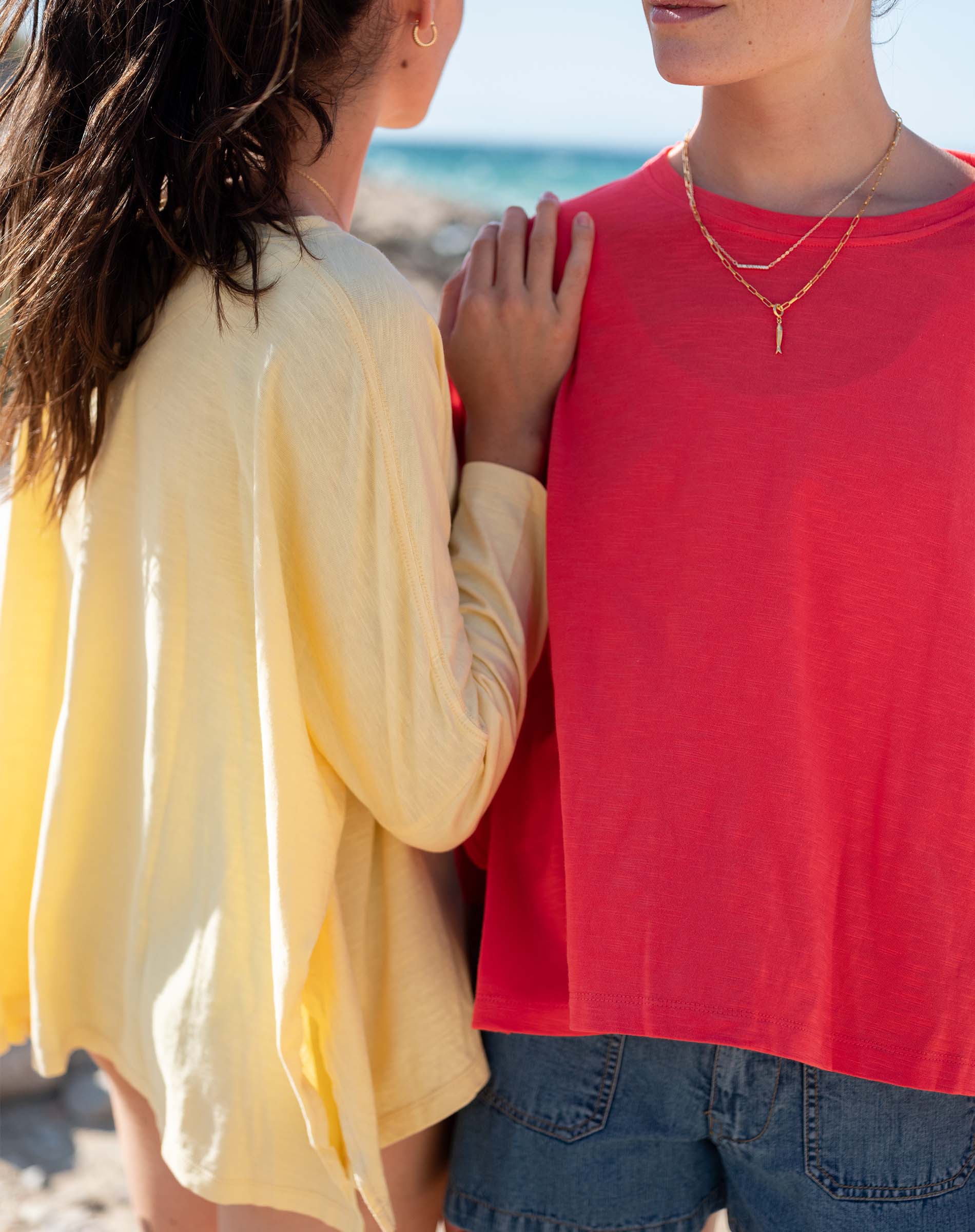 Two people standing close together, one in a yellow shirt and the other in a red shirt, with a blurred background.