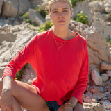 Woman in a red sweater sitting on rocks with a natural background