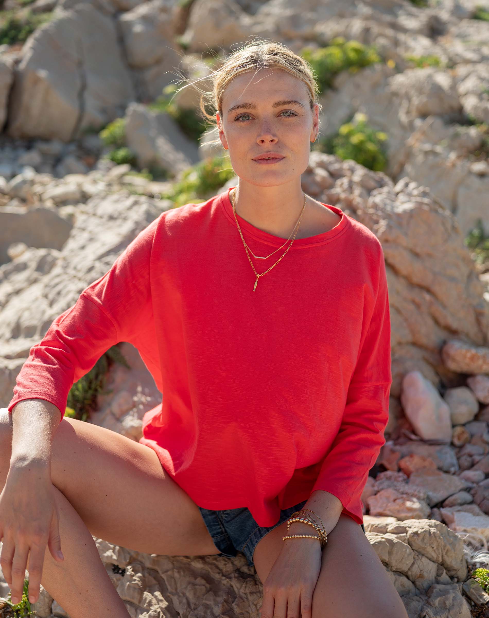 Woman in a red sweater sitting on rocks with a natural background