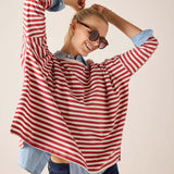 Woman wearing a red and white striped shirt with rolled-up sleeves on a beige background