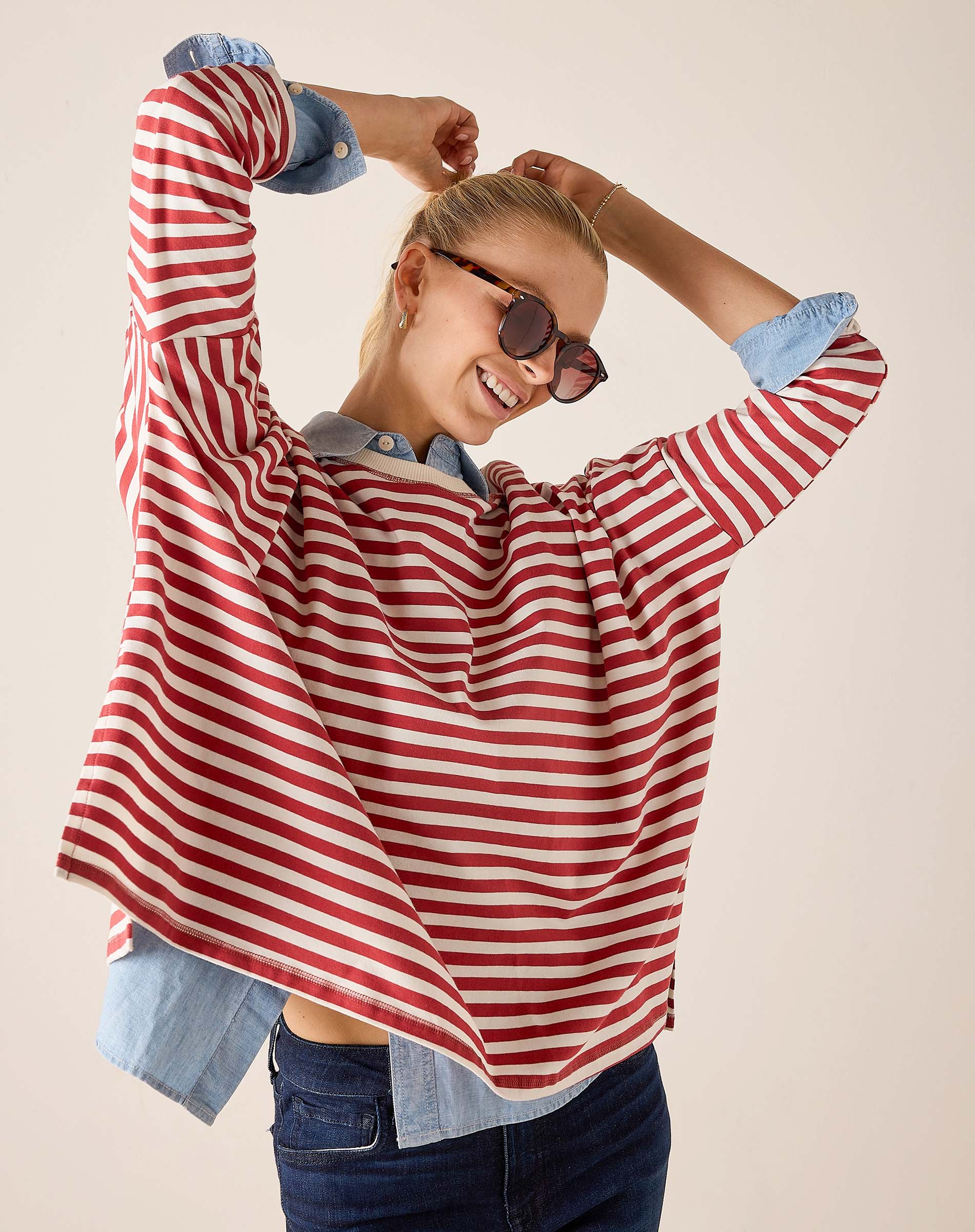 Woman wearing a red and white striped shirt with rolled-up sleeves on a beige background