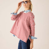 Woman wearing a red and white striped shirt with rolled-up sleeves on a beige background
