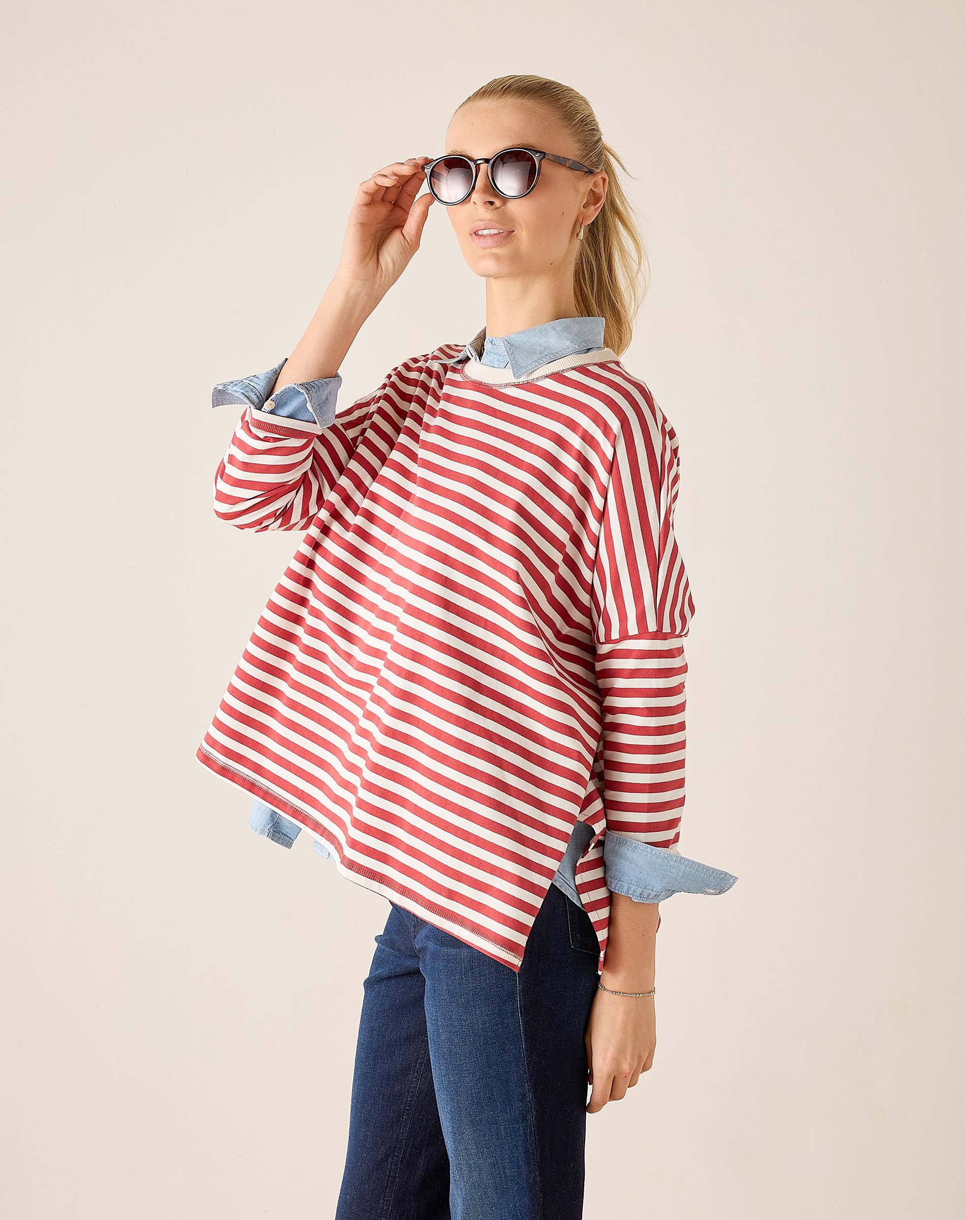 Woman wearing a red and white striped shirt with rolled-up sleeves on a beige background