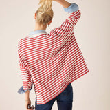 Person wearing a red and white striped shirt with rolled-up sleeves on a plain background