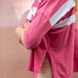 Person wearing a pink jacket with white stripes on a plain background
