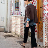 Model wearing an espresso brown slub knit top and black wide-leg trousers in a tiled courtyard.
